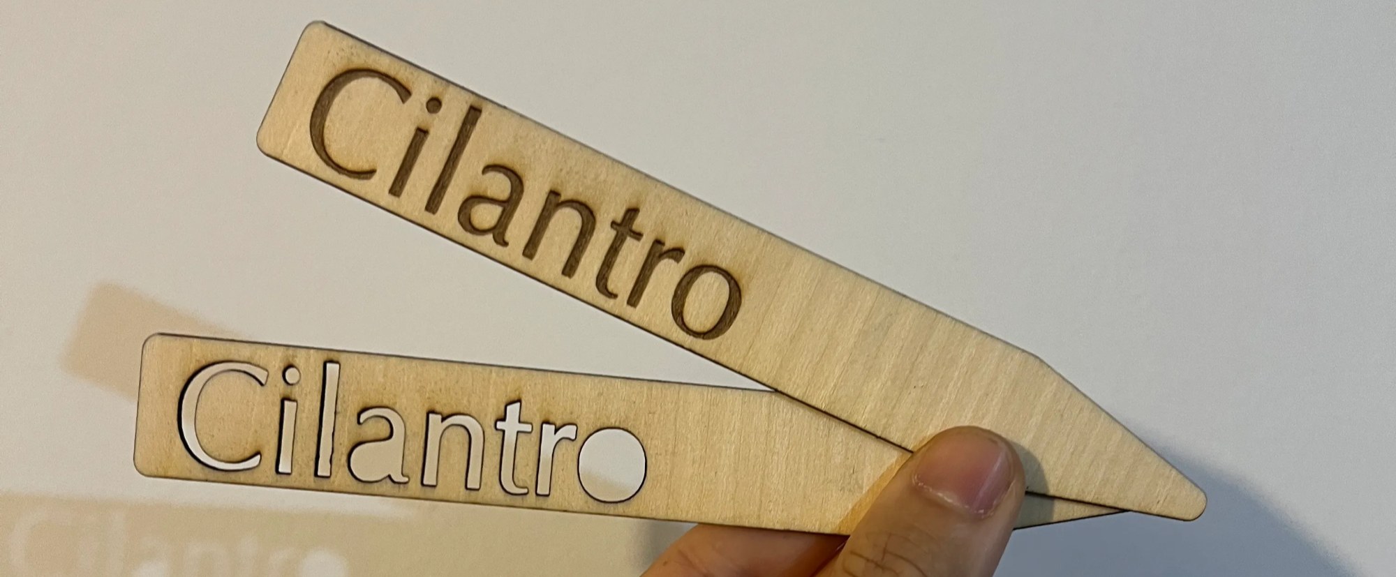 dos marcadores terminados, uno con el nombre cortado y otro grabado